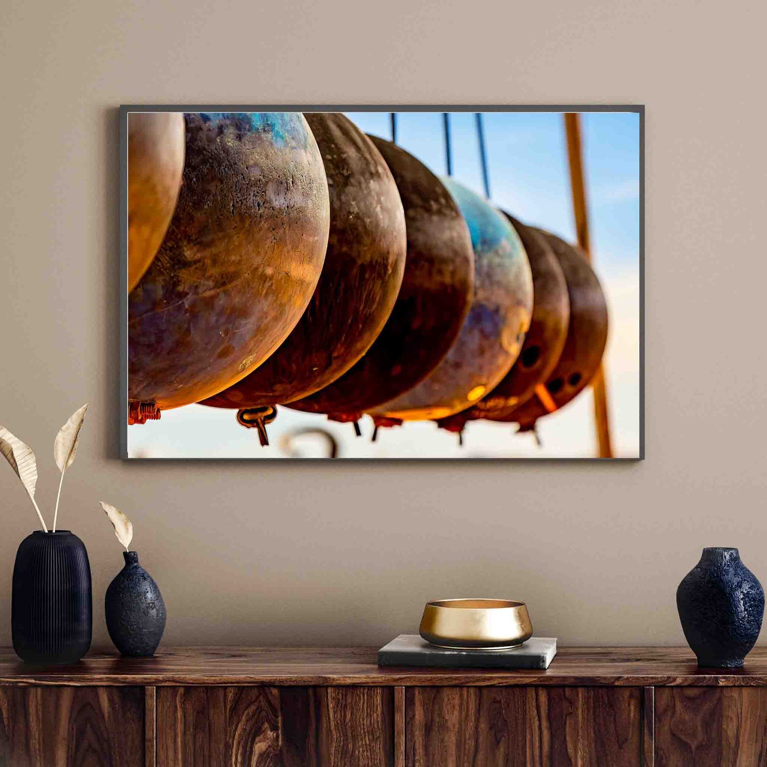 Wall art of Artist Andre Chambers, featuring an image of several rusted bouy's, in a line, suspended in air. The image is framed, on a wall, in a living room of a home.